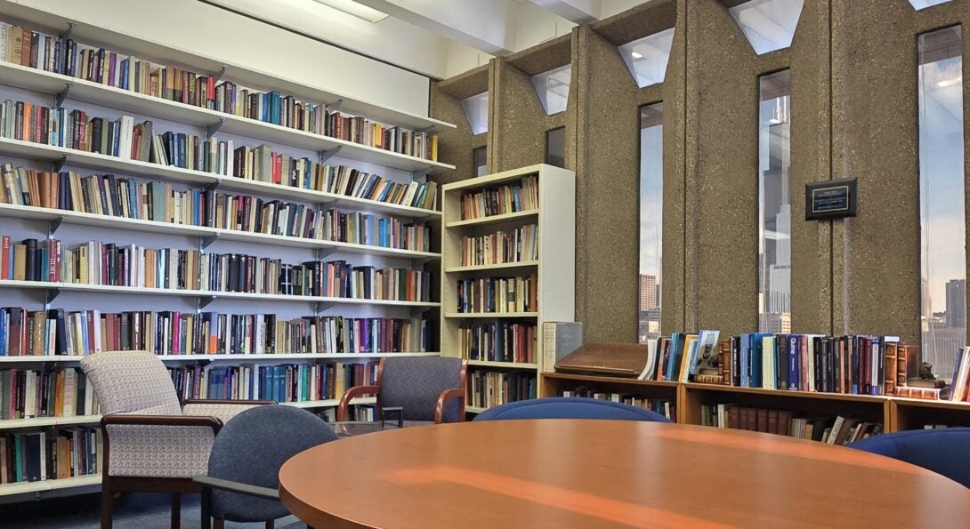 A wall lined with bookshelves and windows with a view of the city.